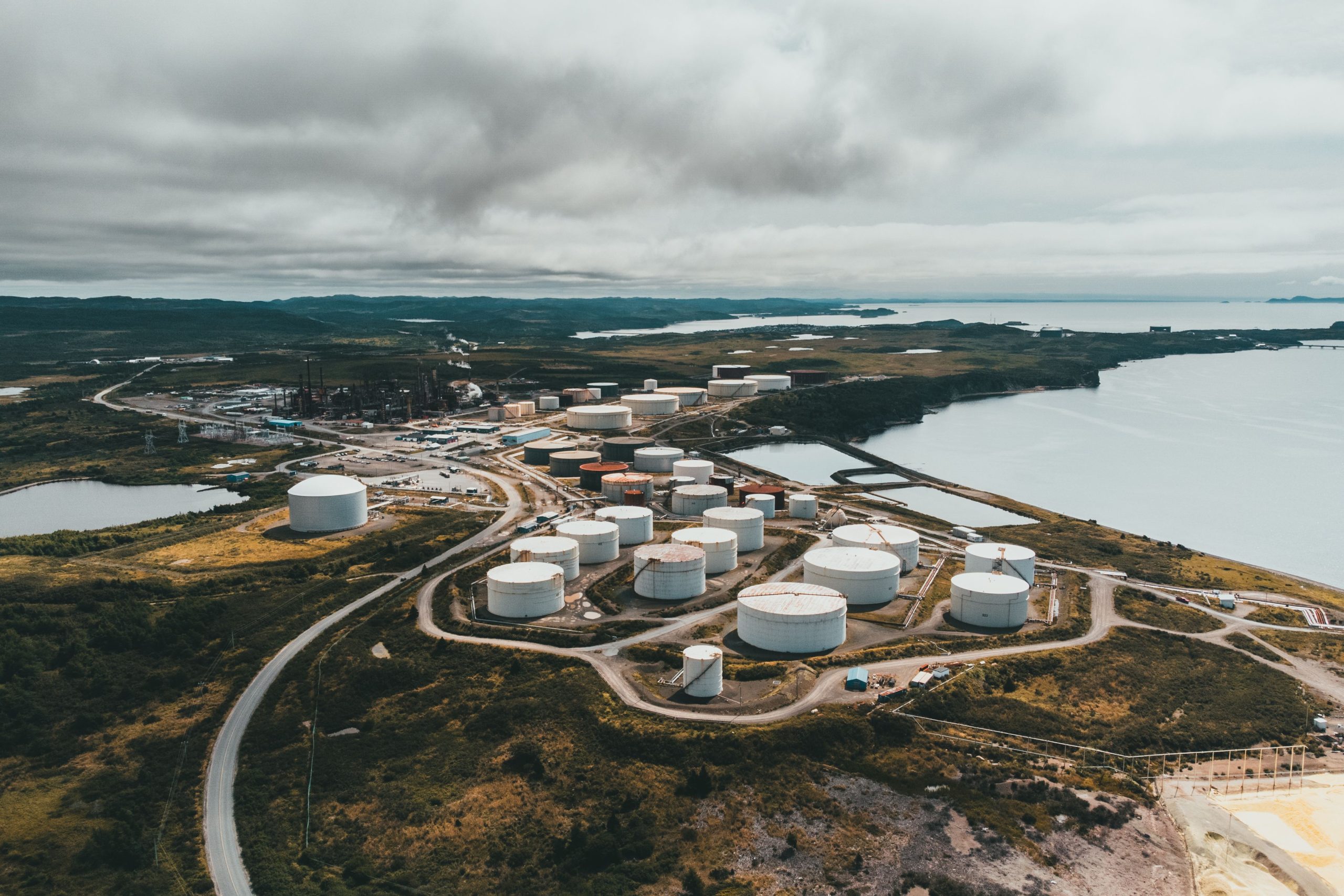Aerial shot of industrial storage tanks near a waterfront landscape, showcasing industrial infrastructure.